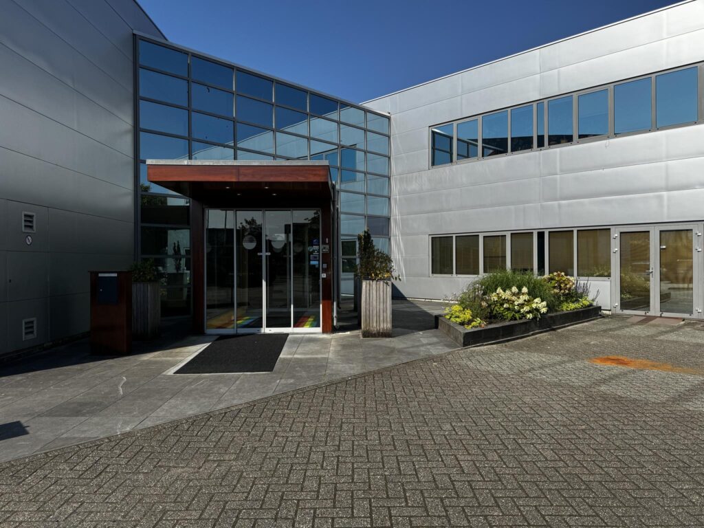 Ingang van een modern kantoorpand aan de Softwareweg met glazen gevel en bloembakken bij de entree.