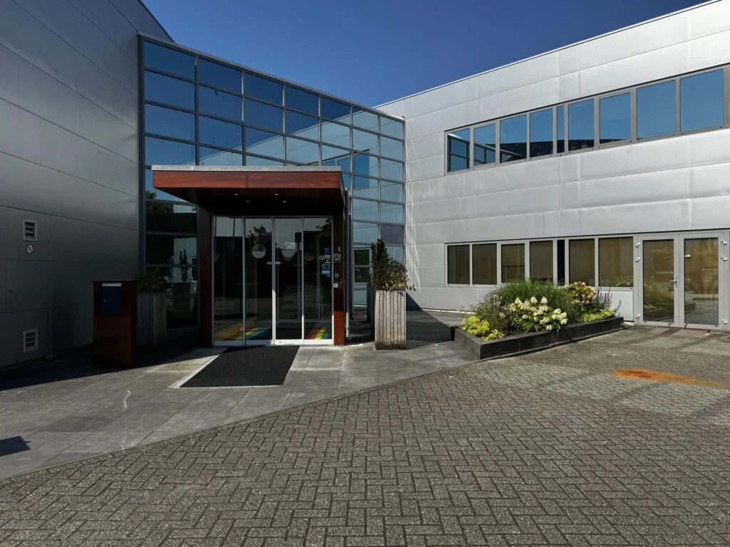 Ingang van een modern kantoorpand aan de Softwareweg met glazen gevel en bloembakken bij de entree.