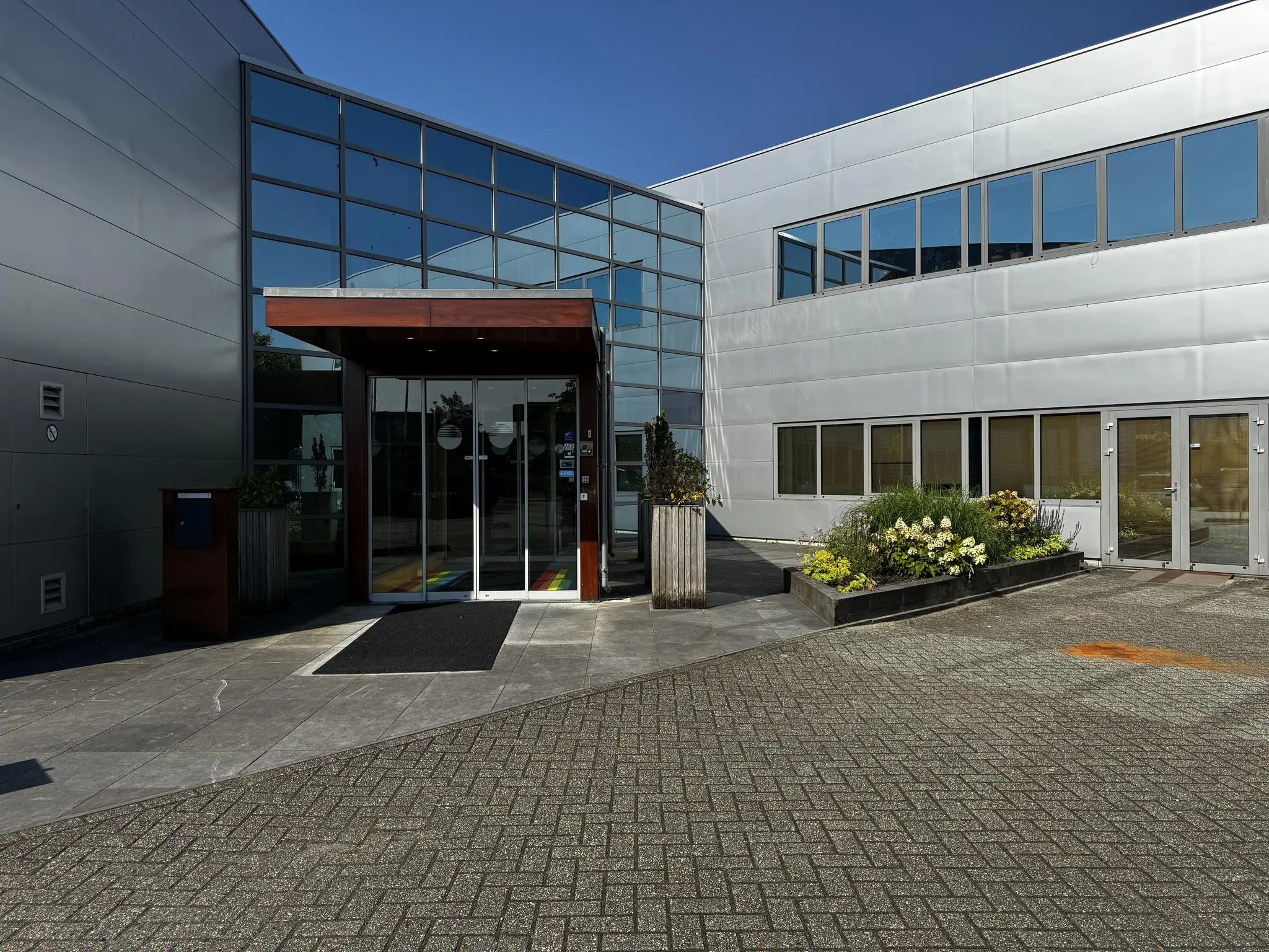 Ingang van een modern kantoorpand aan de Softwareweg met glazen gevel en bloembakken bij de entree.