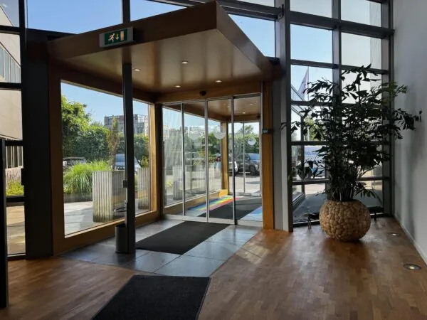 Ingang van een modern kantoorgebouw aan de Softwareweg met glazen schuifdeuren, houten vloer en een grote plantenbak.