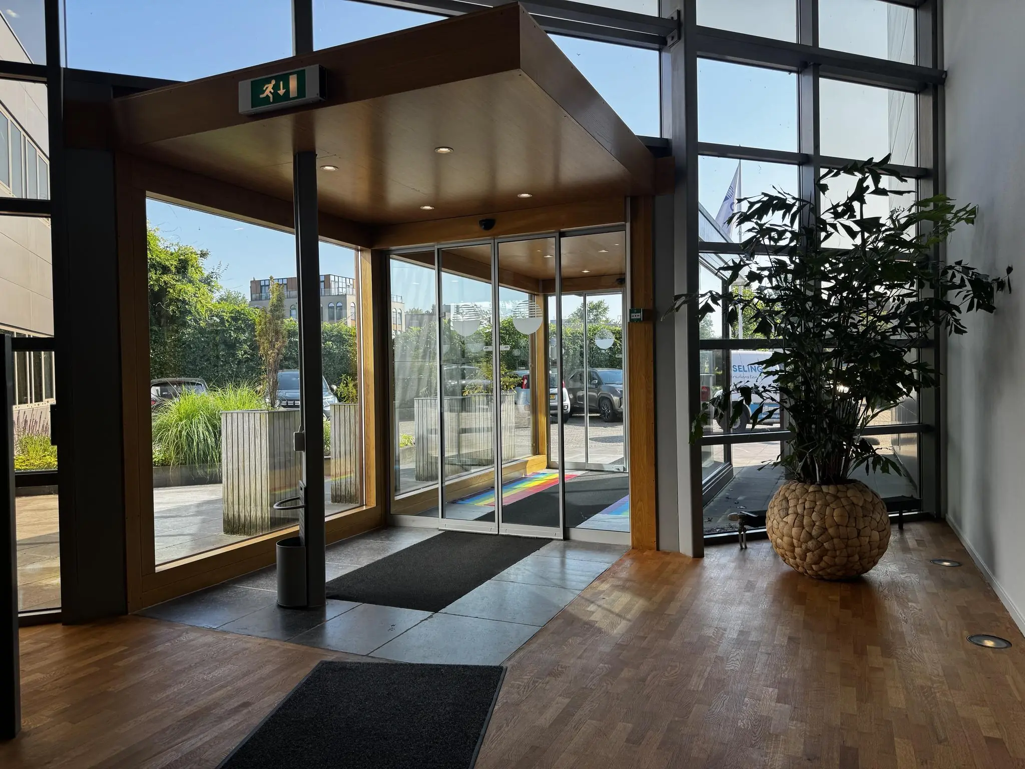 Ingang van een modern kantoorgebouw aan de Softwareweg met glazen schuifdeuren, houten vloer en een grote plantenbak.