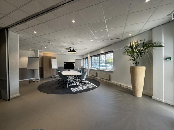Moderne vergaderruimte aan de Softwareweg met ovale tafel, stoelen, flip-overs, groot scherm en veel daglicht.
