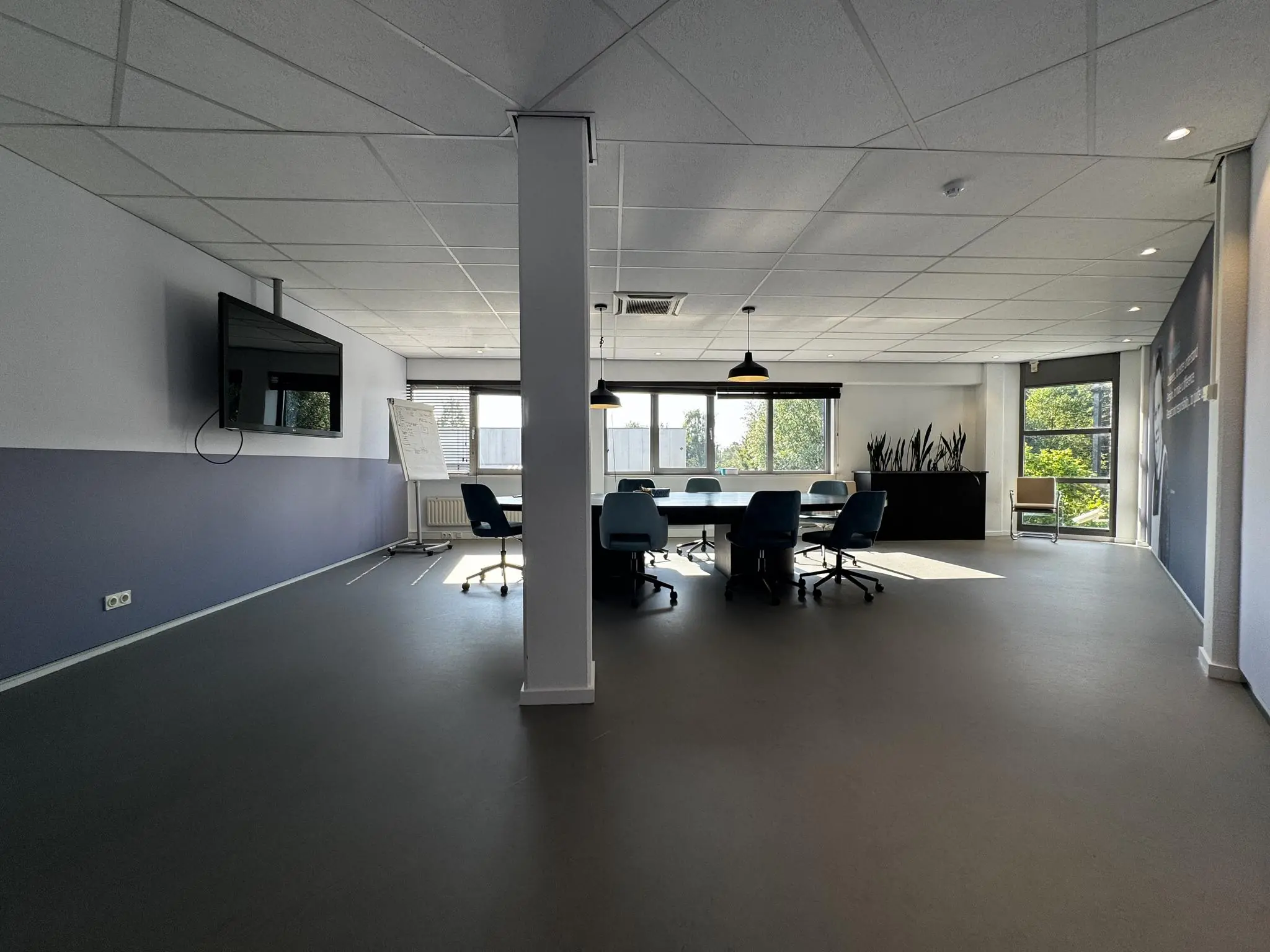 Moderne vergaderruimte op de Softwareweg met vergadertafel, stoelen, tv-scherm en natuurlijk licht door grote ramen.