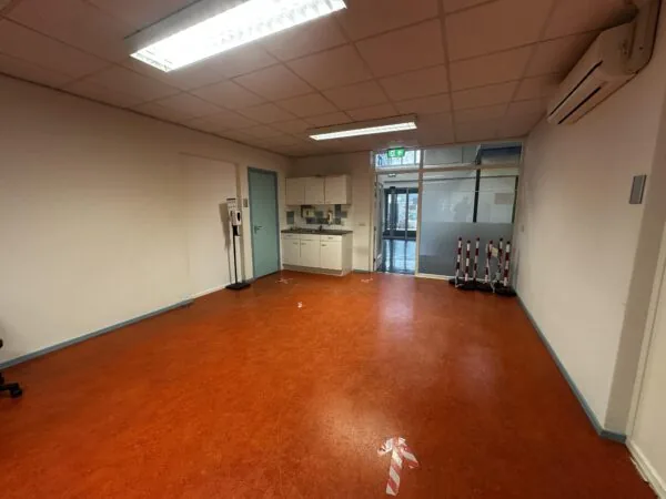 Lege binnenruimte in Veulenkamp met rode vloer, kitchenette en desinfectiezuil.