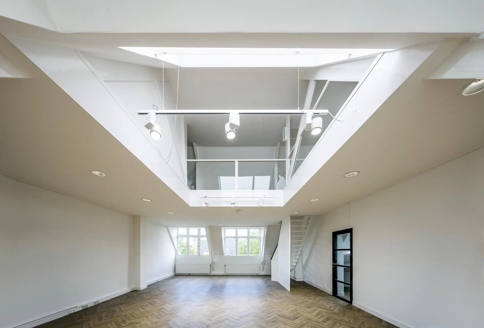 Lichte, moderne loftwoning aan het Emmaplein met houten visgraatvloer en vide met glazen balustrade.