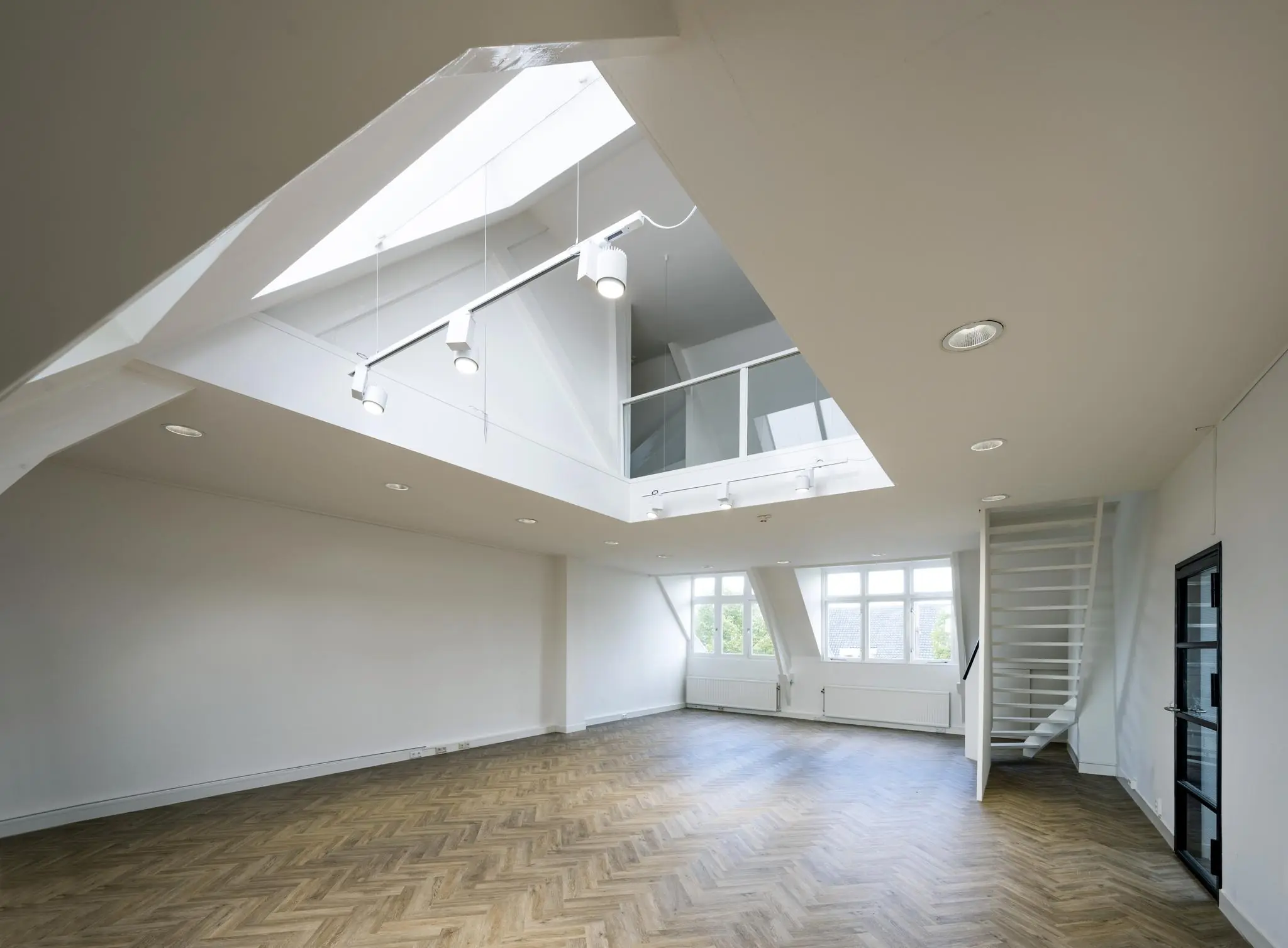 Lichte, moderne loftwoning aan het Emmaplein met visgraatvloer, grote ramen en een open vide met glazen balustrade.