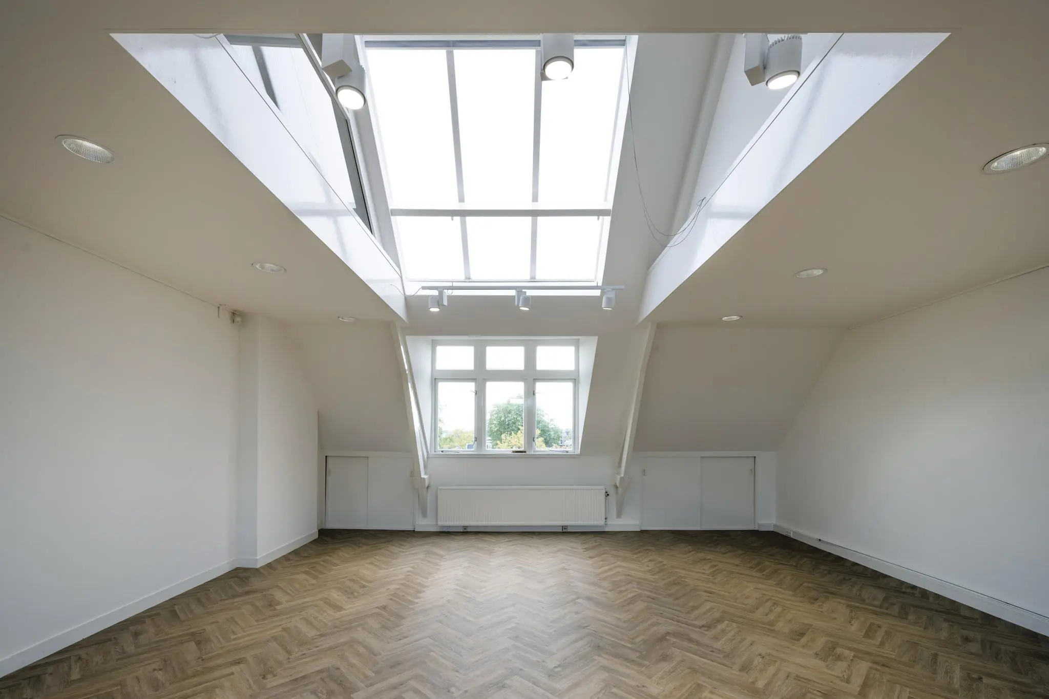 Lichte zolderkamer op het Emmaplein met grote dakramen en visgraat houten vloer.