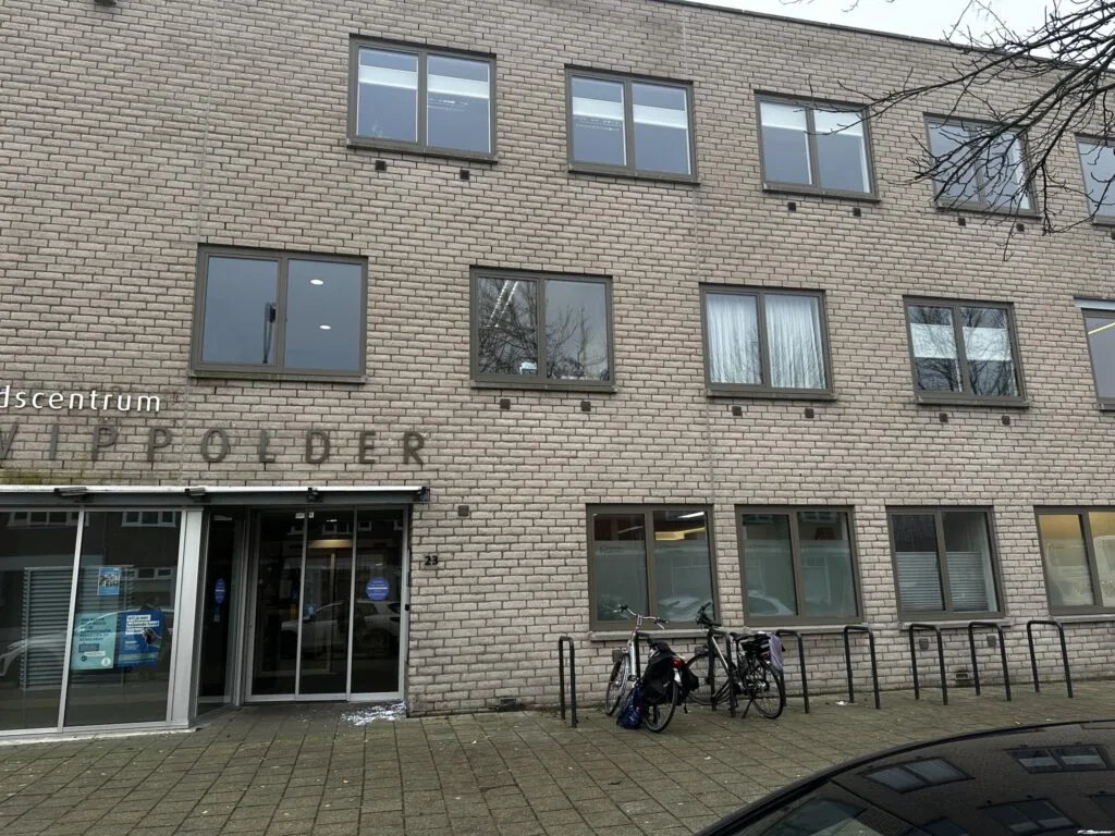 Voorgevel van gezondheidscentrum Vrederust aan de Nassaulaan, met fietsenrek en entree.