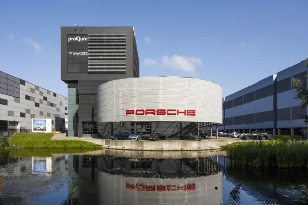 Modern bedrijfsgebouw aan de Sijsjesbergweg met prominente Porsche showroom en weerspiegeling in het water.