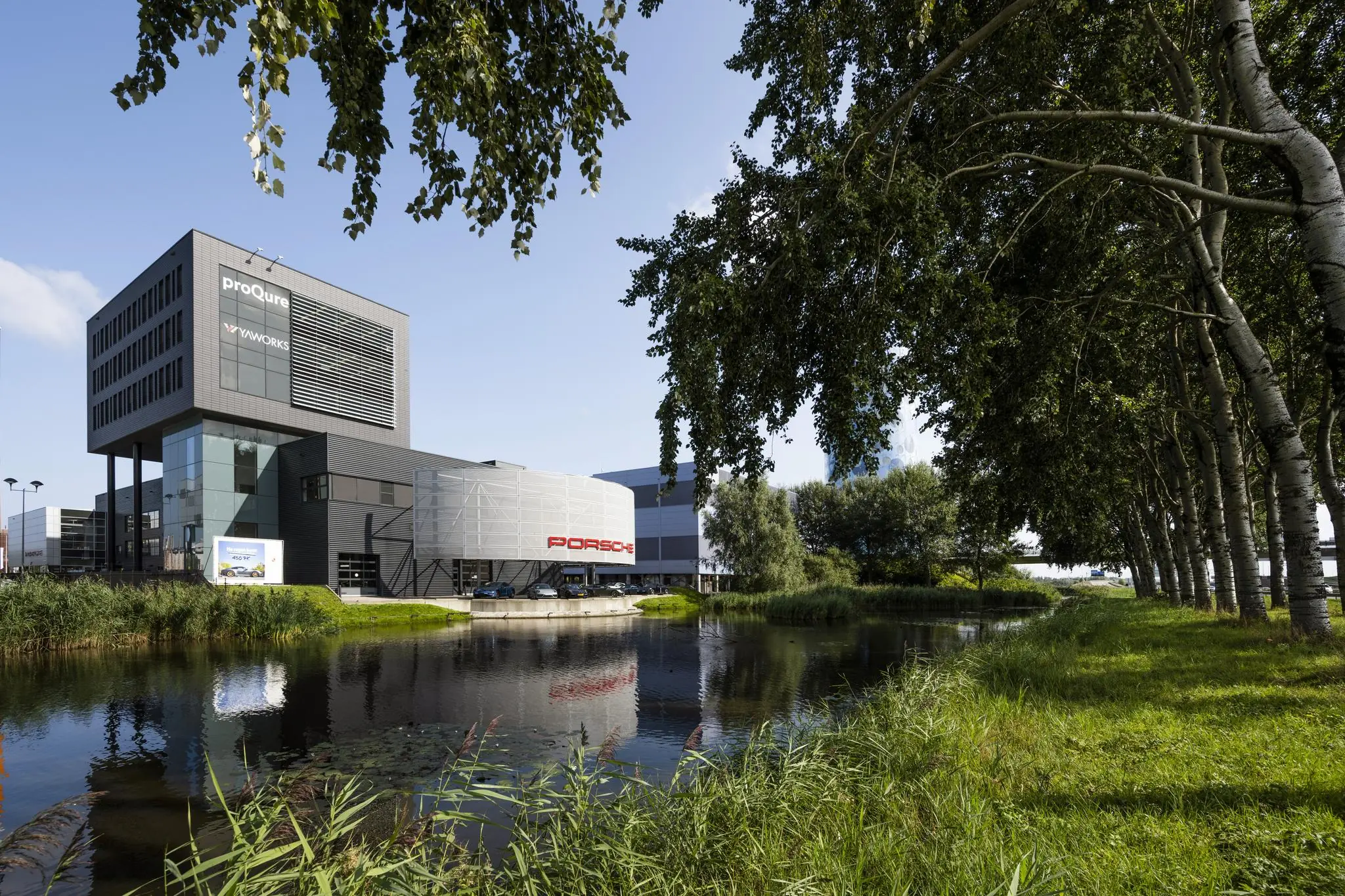Modern bedrijfspand aan de Sijsjesbergweg in Amsterdam met Porsche showroom en vijver op de voorgrond.