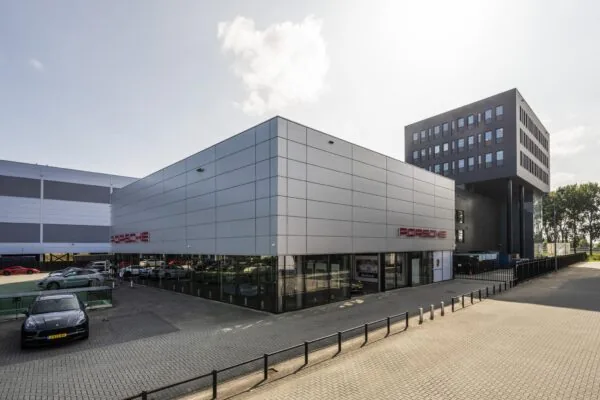 Moderne Porsche-dealer aan de Sijsjesbergweg met showroom en meerdere geparkeerde auto’s.