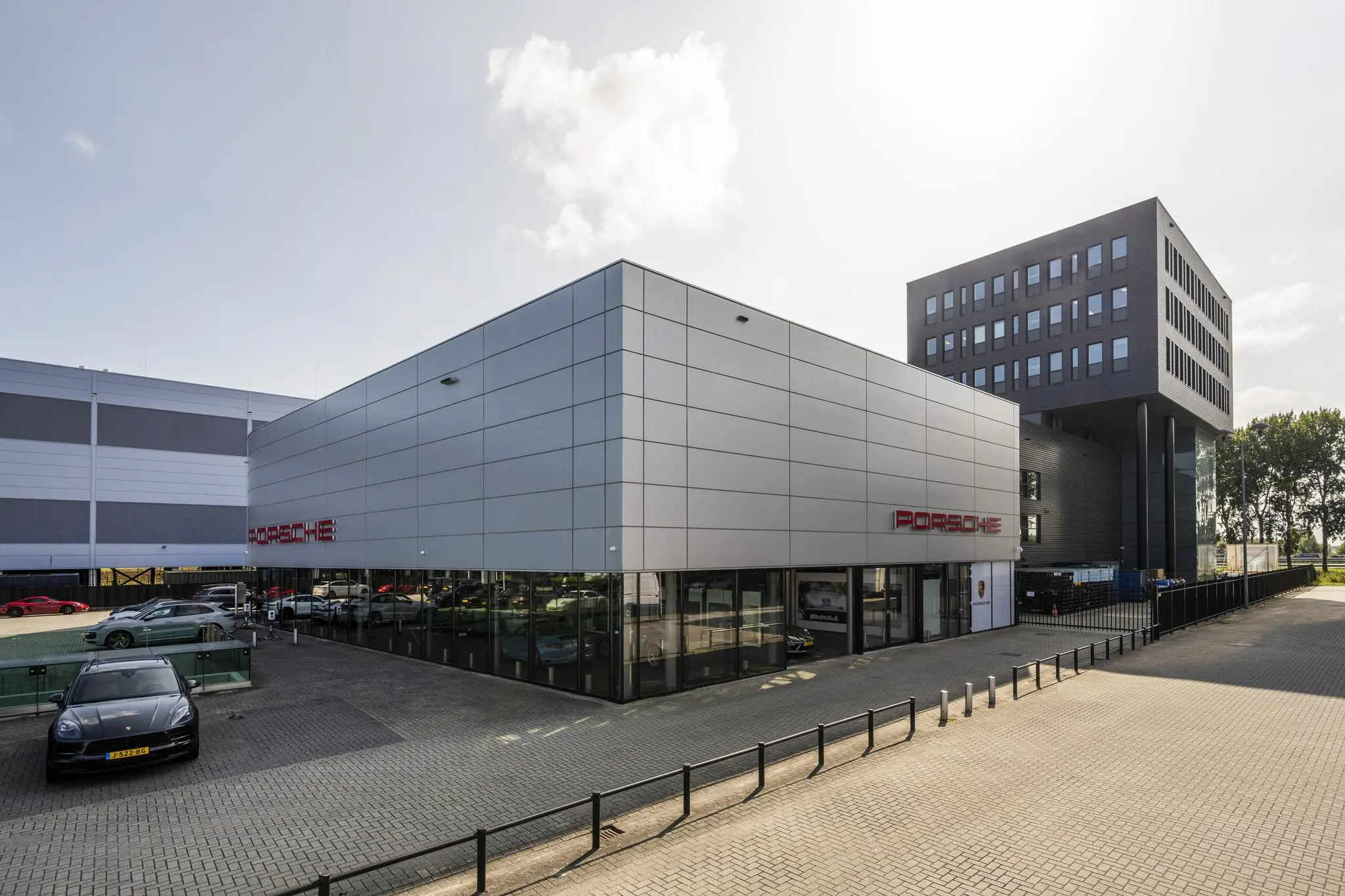 Moderne Porsche-dealer aan de Sijsjesbergweg met showroom en meerdere geparkeerde auto’s.
