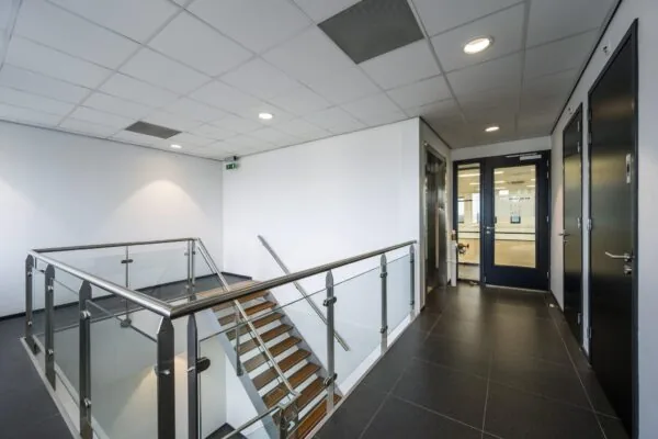 Moderne trapopgang en gang op de Sijsjesbergweg met glazen balustrade en donkere deuren.