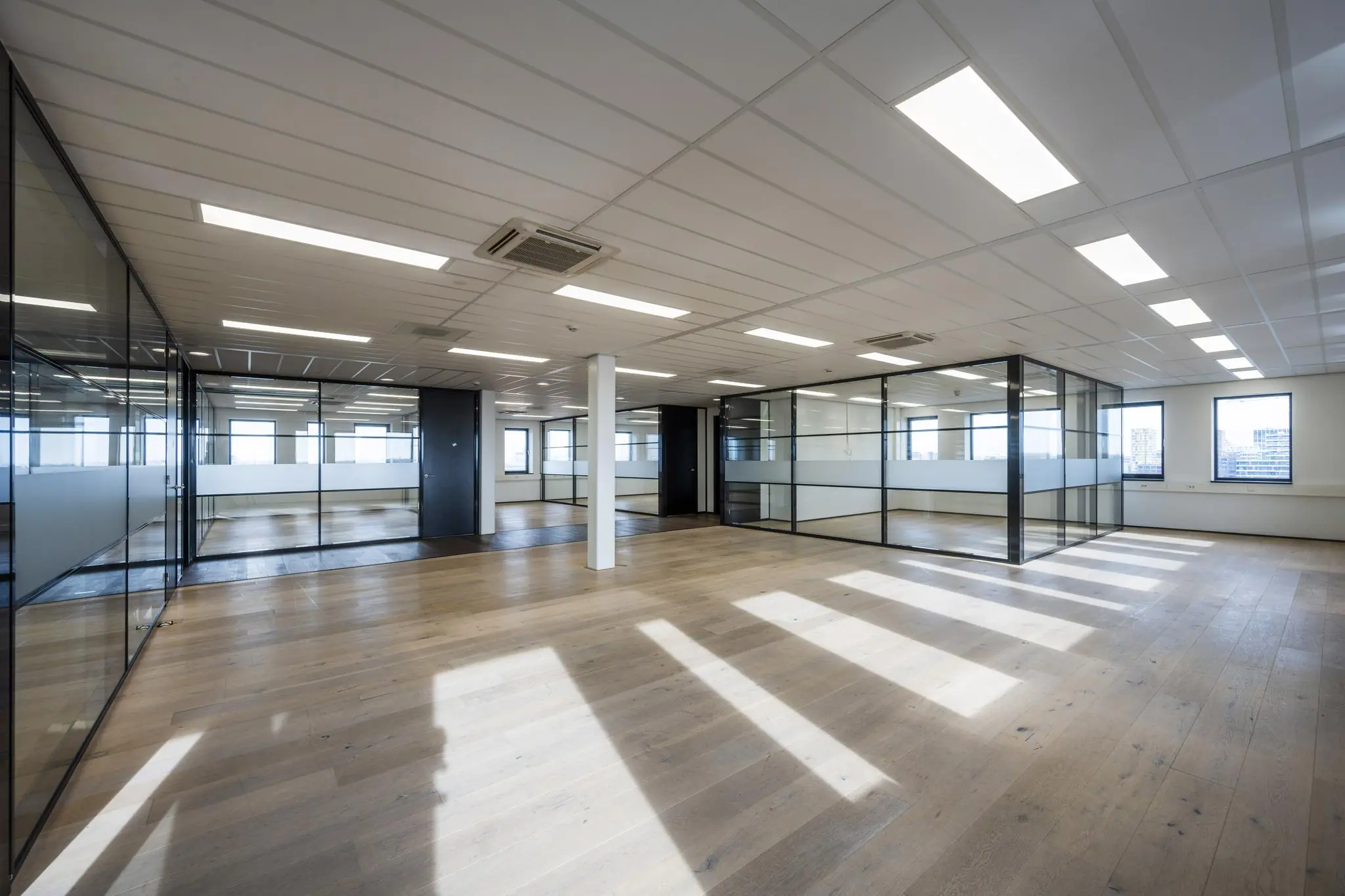 Licht en modern kantoorinterieur aan de Sijsjesbergweg met glazen wanden en houten vloer.