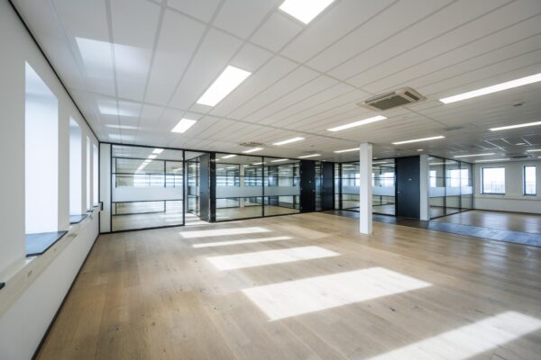 Licht, modern kantoorinterieur aan de Sijsjesbergweg met glazen wanden en houten vloer.