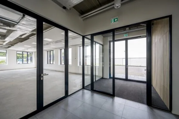 Moderne, lege kantoorruimte aan de Nicolaas Tetterodestraat met glazen binnenwanden en zicht op de buitendeur.