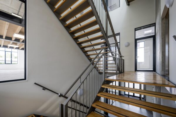Moderne houten trap met metalen leuning in een licht trappenhuis aan de Nicolaas Tetterodestraat.