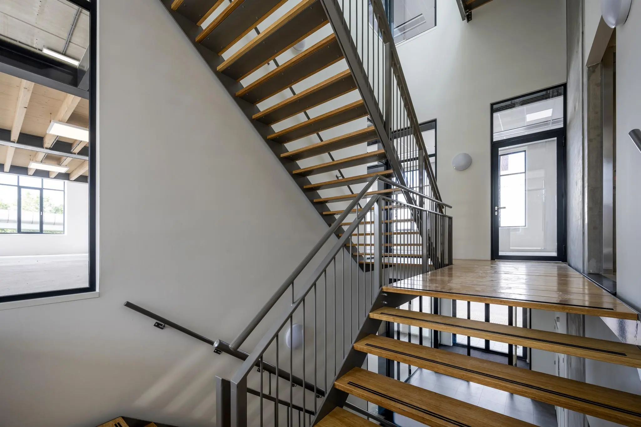 Moderne houten trap met metalen leuning in een licht trappenhuis aan de Nicolaas Tetterodestraat.