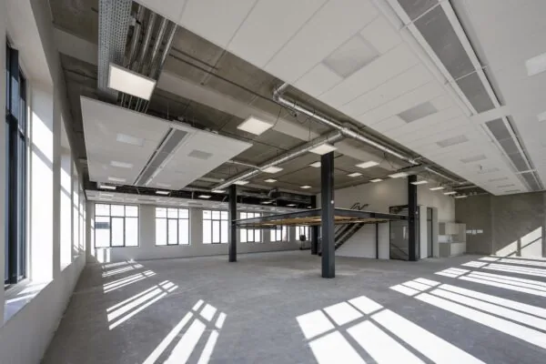Licht industrieel bedrijfsruimte-interieur aan de Nicolaas Tetterodestraat met betonnen vloer, grote ramen en een entresolvloer.