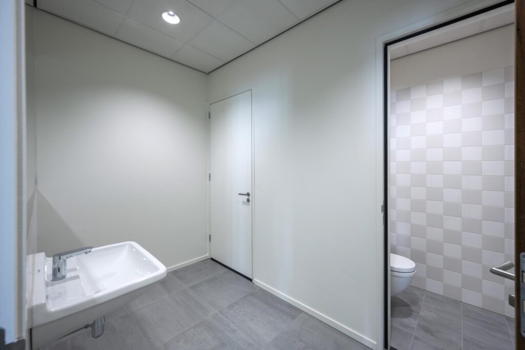 Moderne, minimalistisch ingerichte toiletruimte aan de Nicolaas Tetterodestraat met grijze vloertegels en een zwevend toilet.