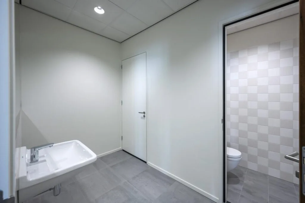 Moderne, minimalistisch ingerichte toiletruimte aan de Nicolaas Tetterodestraat met grijze vloertegels en een zwevend toilet.