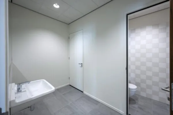 Moderne, minimalistisch ingerichte toiletruimte aan de Nicolaas Tetterodestraat met grijze vloertegels en een zwevend toilet.