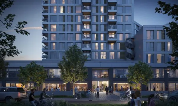 Moderne woontoren aan de H.J.E. Wenckebachweg in de schemering met verlichte ramen, terrassen en mensen op straat.