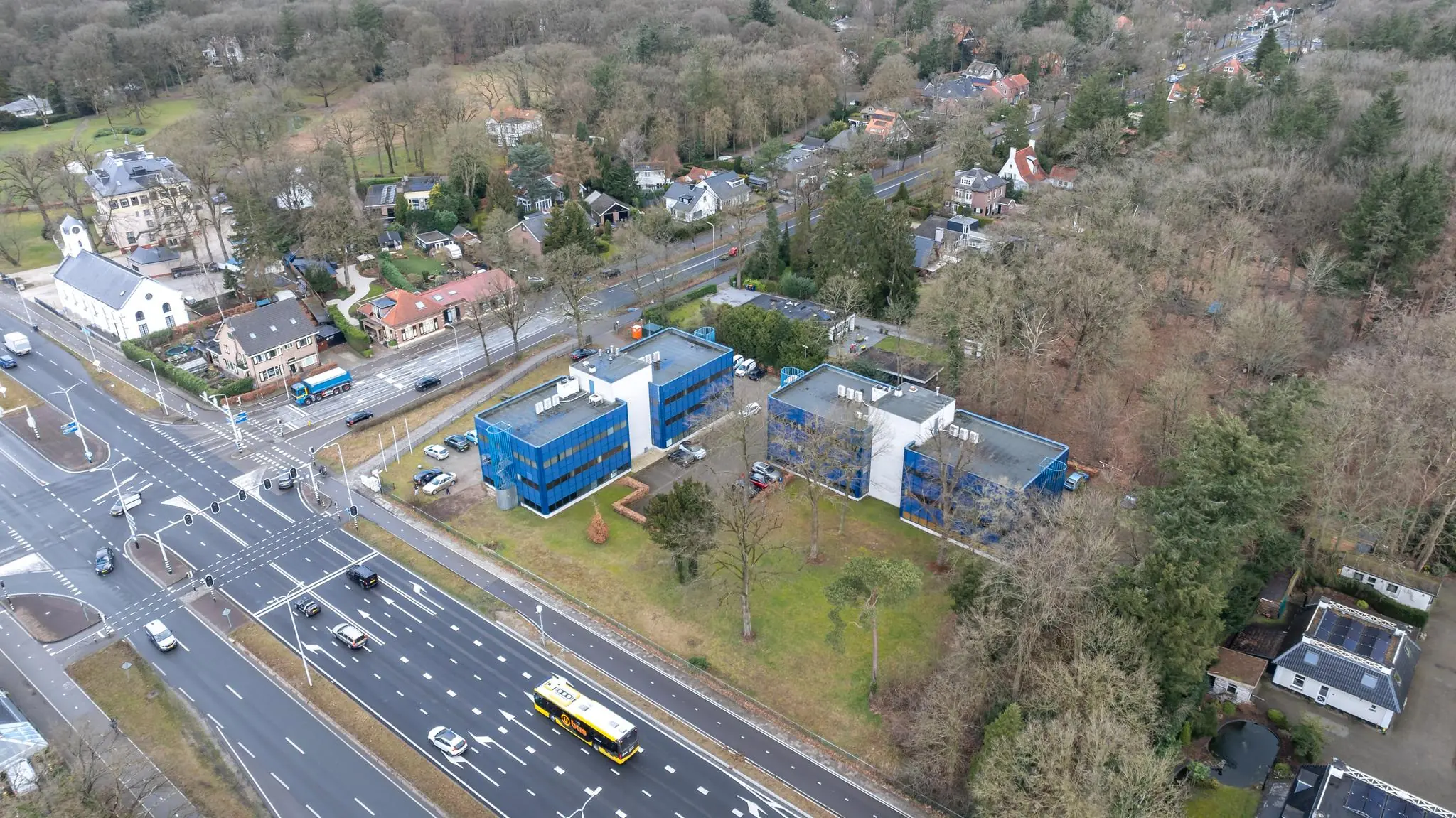 Luchtfoto van kantoren aan de Dolderseweg in een bosrijke omgeving bij een druk kruispunt.