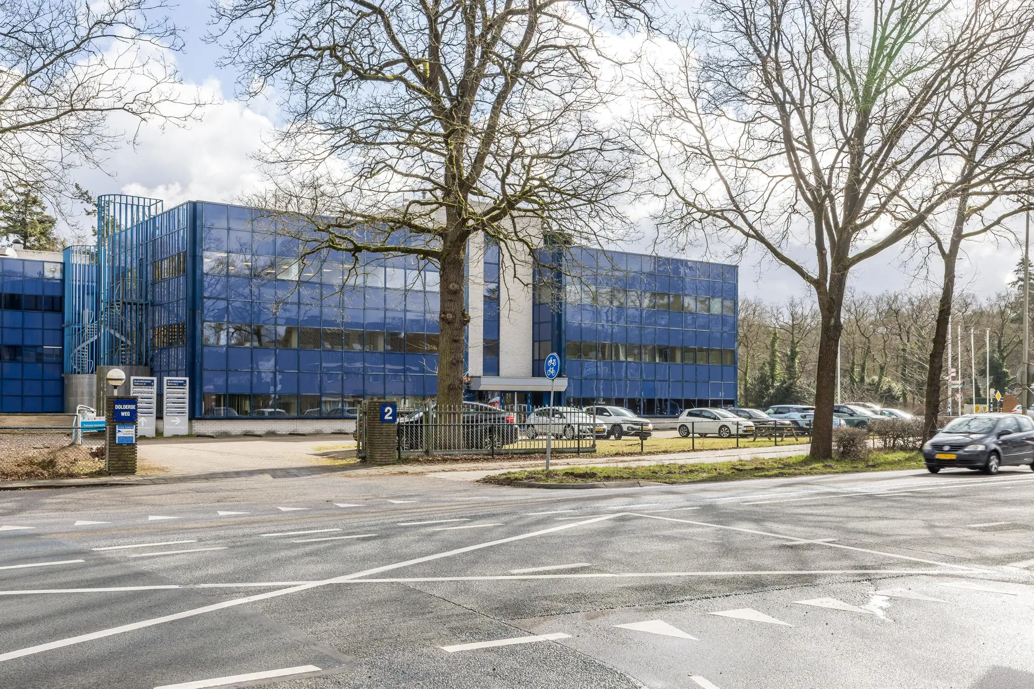 Modern kantoorgebouw aan de Dolderseweg 2 met blauwe gevel en omringende parkeerplaatsen.