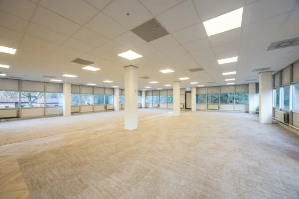 Licht en ruim leeg kantoor aan de Dolderseweg met grote ramen en systeemplafond.