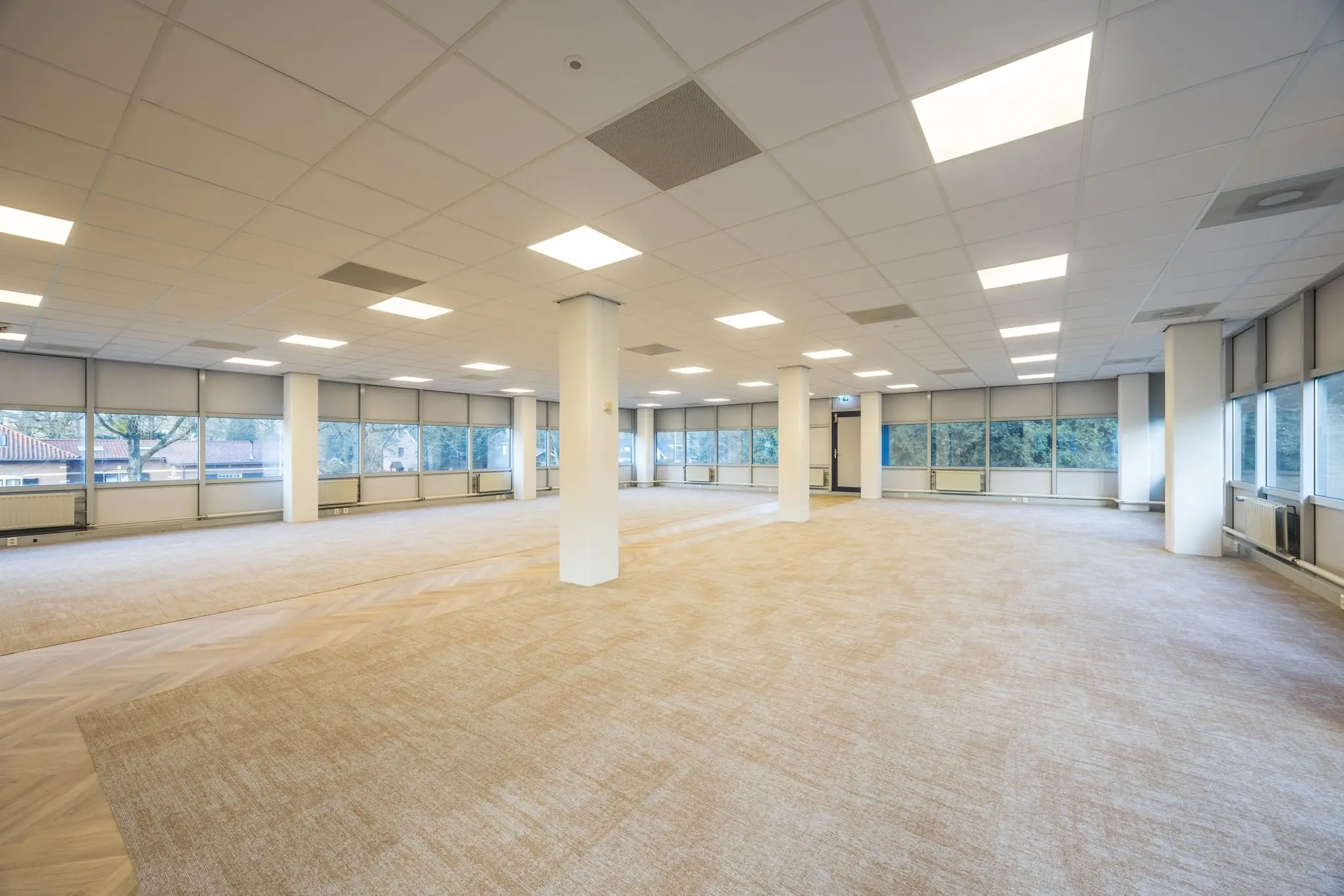 Licht en ruim leeg kantoor aan de Dolderseweg met grote ramen en systeemplafond.