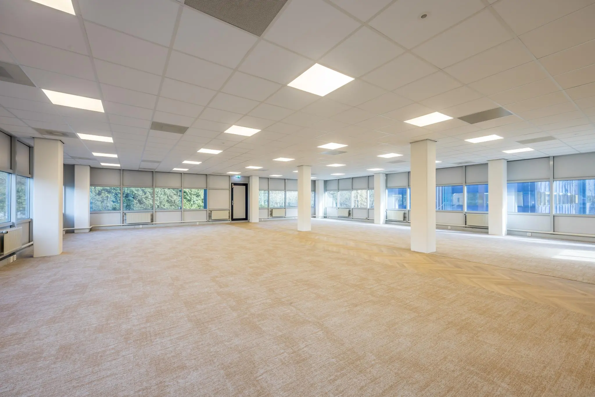 Ruime, lichte kantoorruimte aan de Dolderseweg met tapijtvloer, systeemplafond en grote ramen met rolgordijnen.