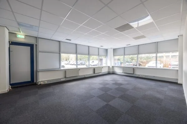 Lege kantoorruimte aan de Dolderseweg met tapijttegels, systeemplafond en grote ramen met zonwering.