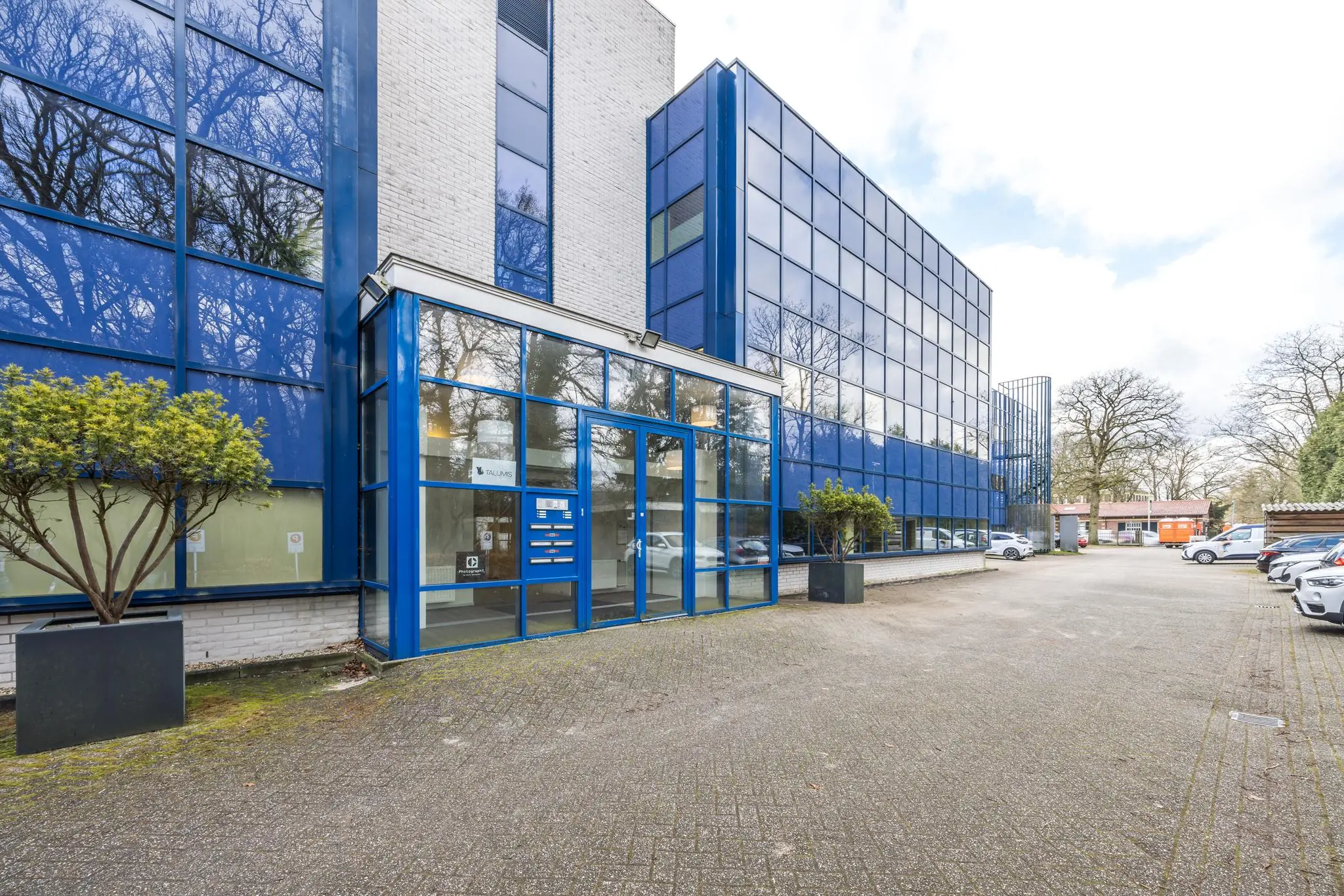 Moderne kantoorgebouw aan de Dolderseweg met blauwe gevel en parkeerplaatsen aan de voorzijde.