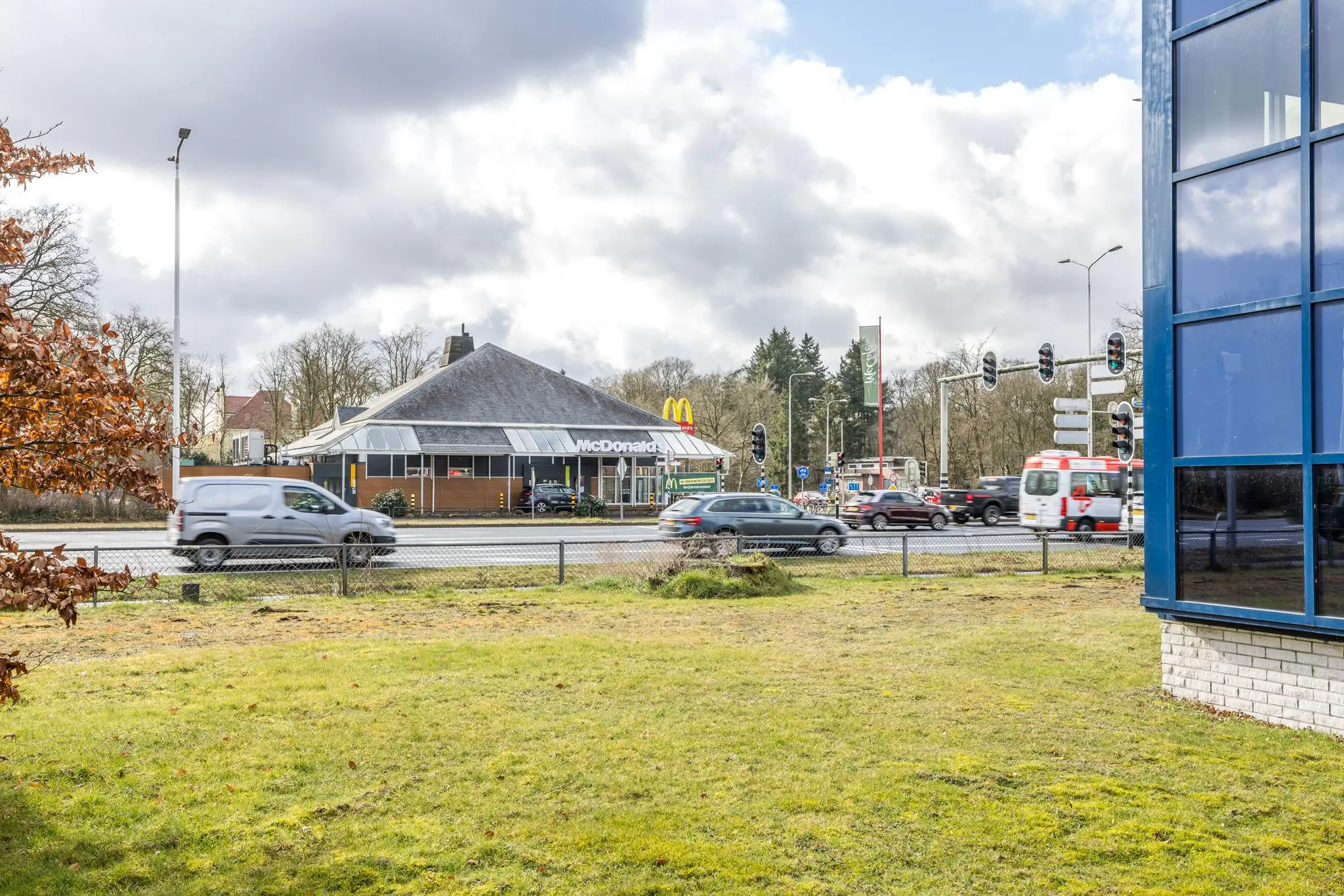 Drukke kruising bij McDonald's aan de Dolderseweg met voorbijrijdend verkeer en gedeeltelijk zicht op een kantoorgebouw.