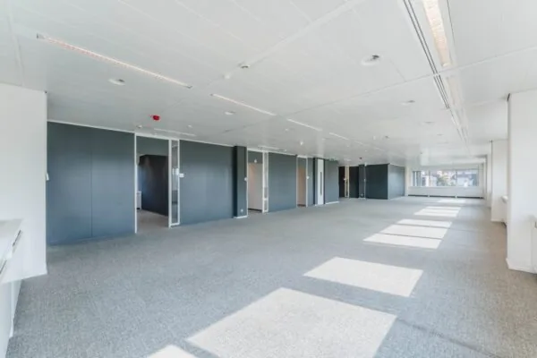 Ruim en licht kantoorinterieur aan de Laarderhoogtweg met grijze vloerbedekking en witte systeemplafonds.