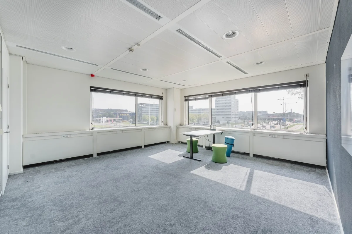 Lichte, lege kantoorruimte aan de Laarderhoogtweg met uitzicht op omliggende kantoorgebouwen en een IKEA-filiaal.