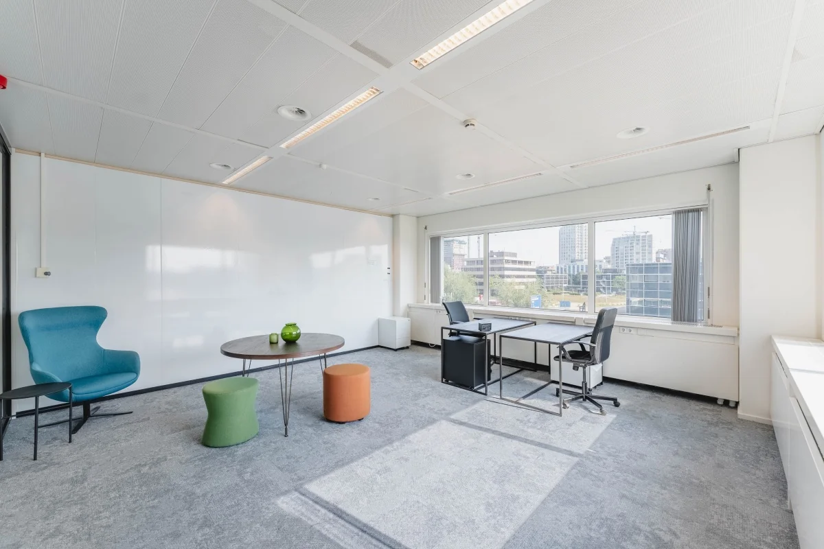 Moderne, lichte kantoorruimte aan de Laarderhoogtweg met zitgedeelte, bureau en uitzicht op omliggende kantoorpanden.