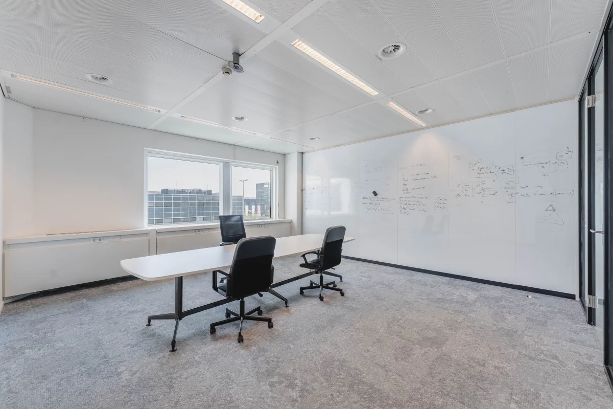 Moderne vergaderruimte aan de Laarderhoogtweg met witte schrijfmuur, tafel en twee bureaustoelen.