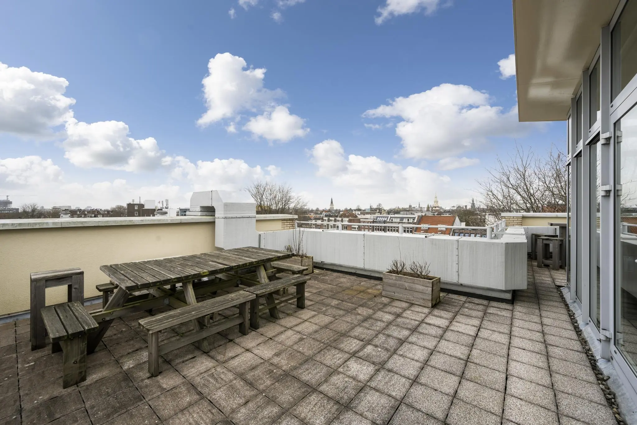 Ruim dakterras aan de Prins Hendrikkade met houten picknicktafels en uitzicht over de stad.