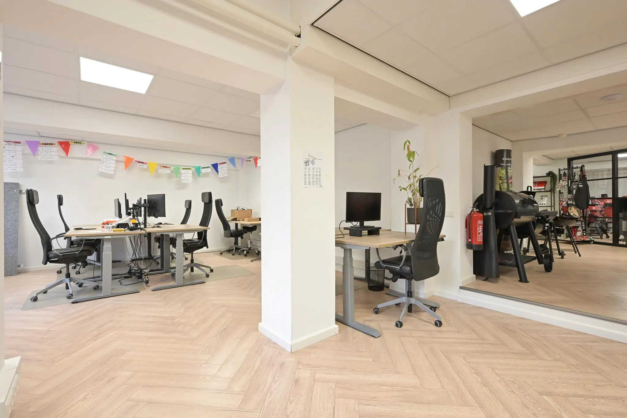 Moderne kantoorruimte aan het Lange Voorhout met werkplekken, computers, versiering en een barbecue in de hoek.