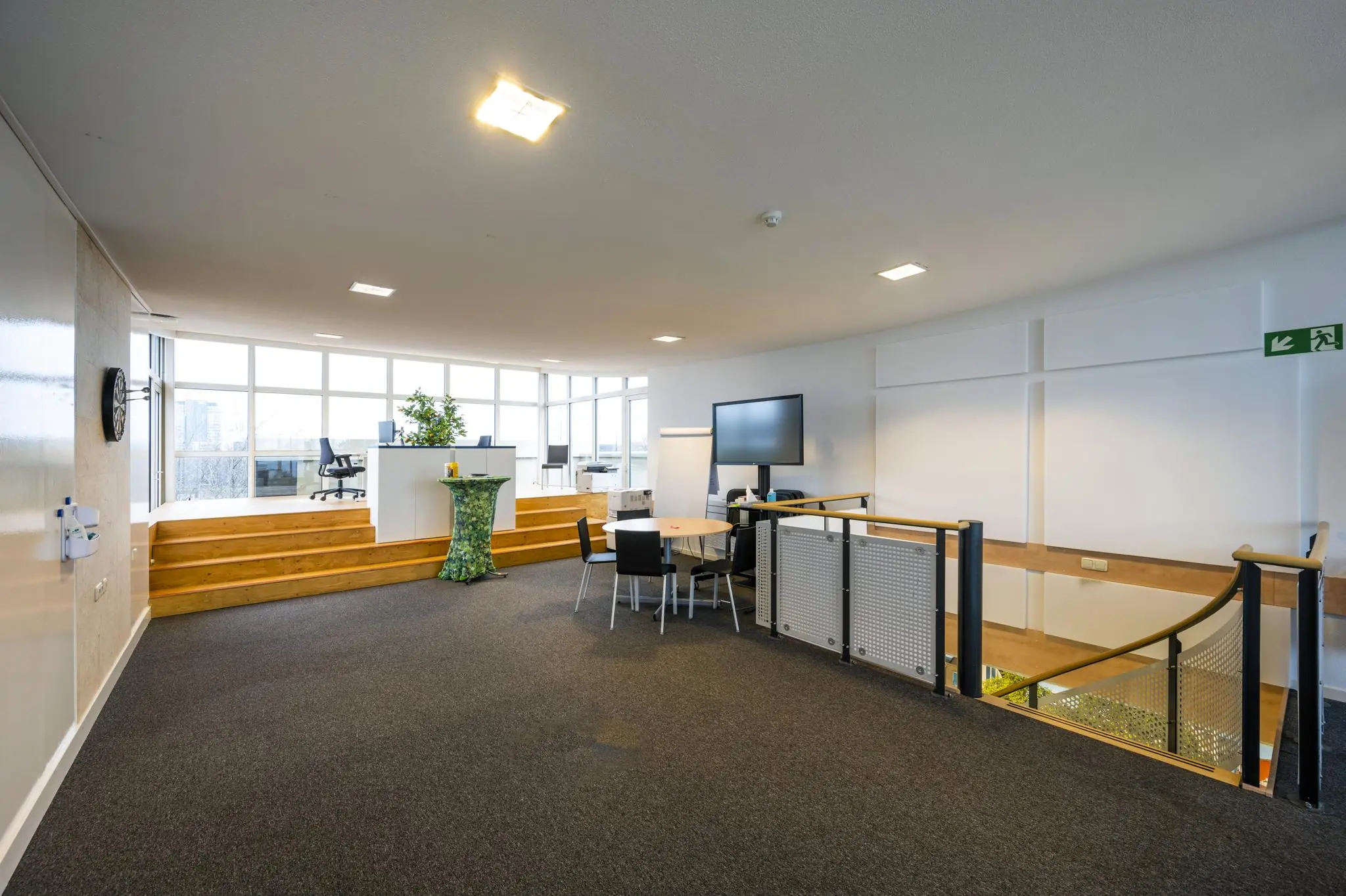 Moderne kantoorruimte aan de Prins Hendrikkade met verhoogd werkgedeelte, vergadertafel en grote ramen met uitzicht.