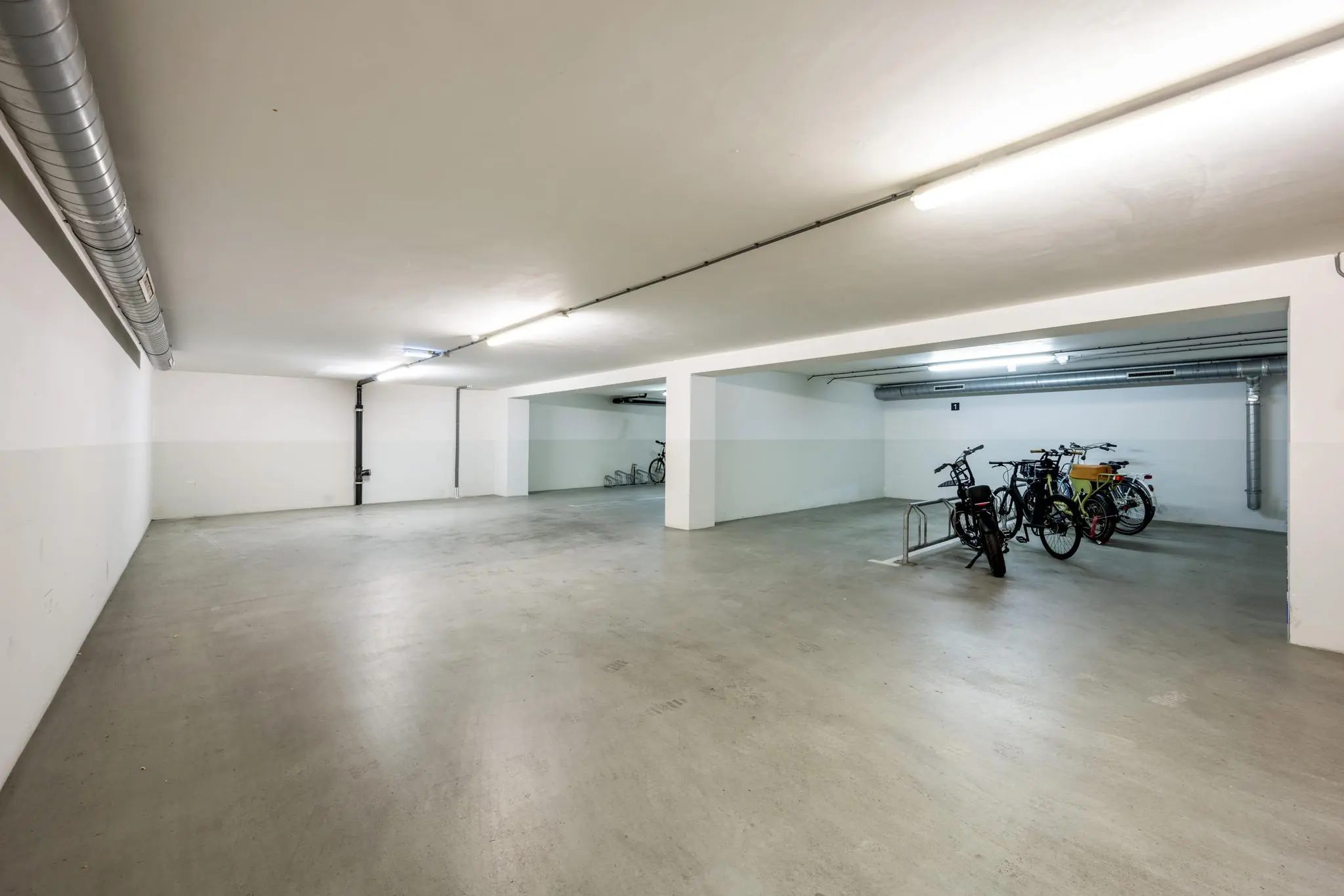 Ondergrondse fietsenstalling aan de Prins Hendrikkade met enkele geparkeerde fietsen en betonnen vloer.