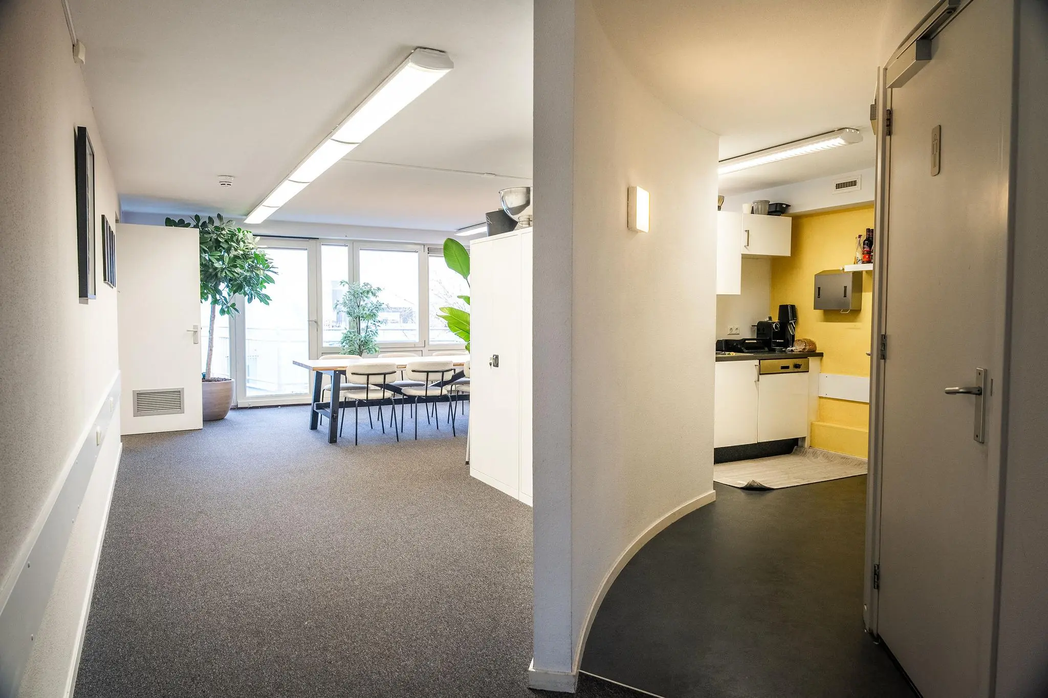 Kantoorruimte aan de Prins Hendrikkade met een vergadertafel, planten en een kleine keukenhoek.