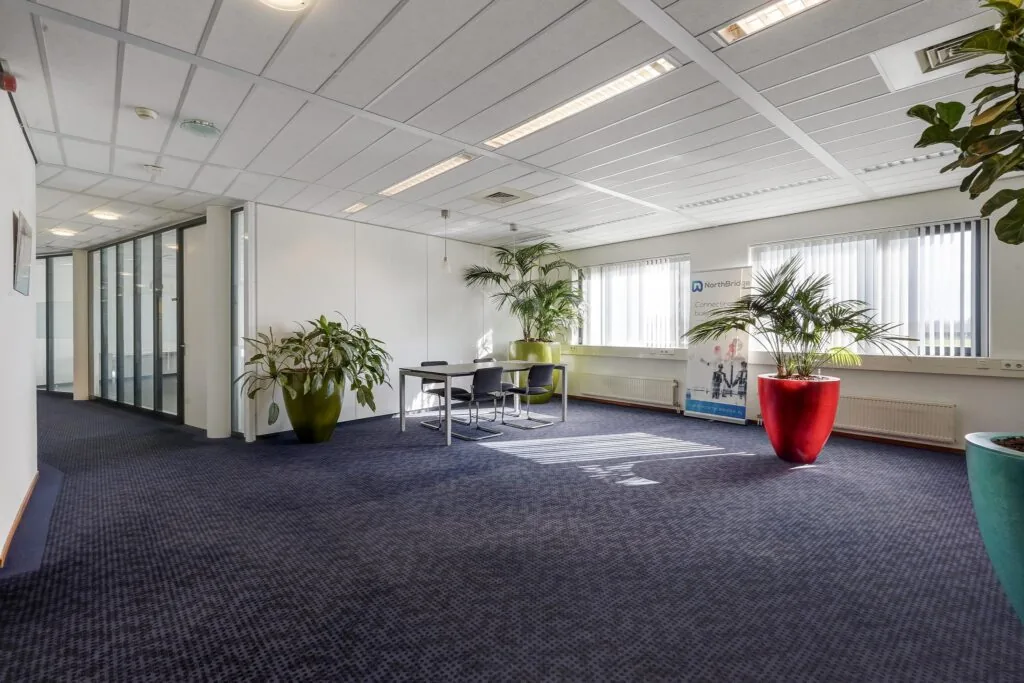 Moderne kantoorruimte aan de Laan van ’s-Gravenmade met vergadertafel, grote planten en natuurlijk licht.