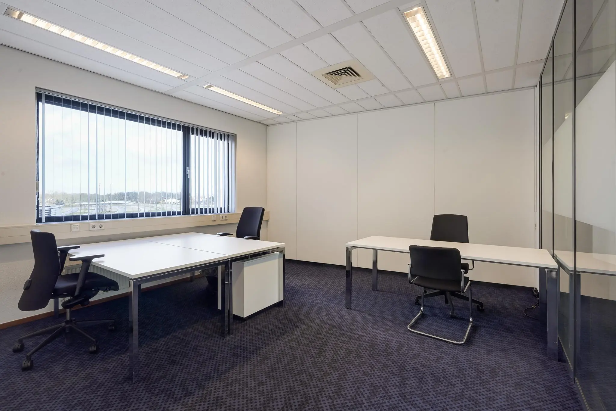 Modern, licht kantoor met drie bureaus en zwarte bureaustoelen aan de Laan van s-Gravenmade.