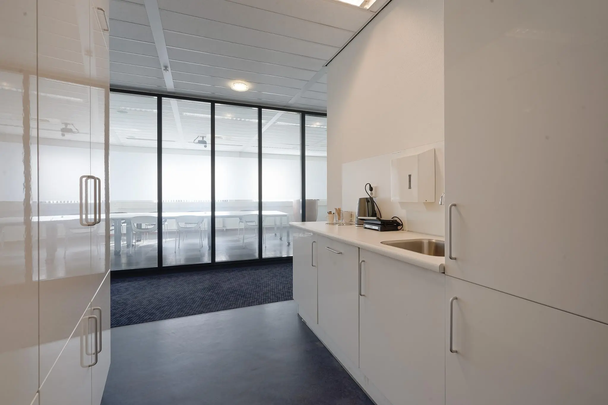 Moderne kitchenette met koffiezetapparaat en spoelbak in een kantoorruimte aan de Laan van ’s-Gravenmade.