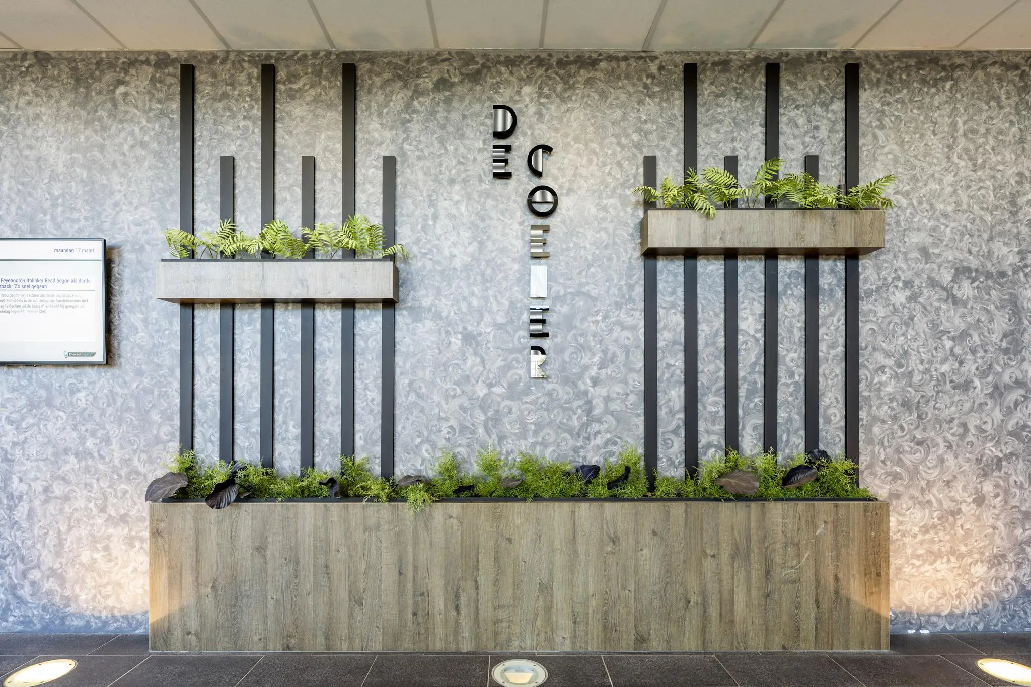 Moderne muurdecoratie met plantenbakken en verticale zwarte lamellen in de entree van het gebouw aan de Overschiestraat.