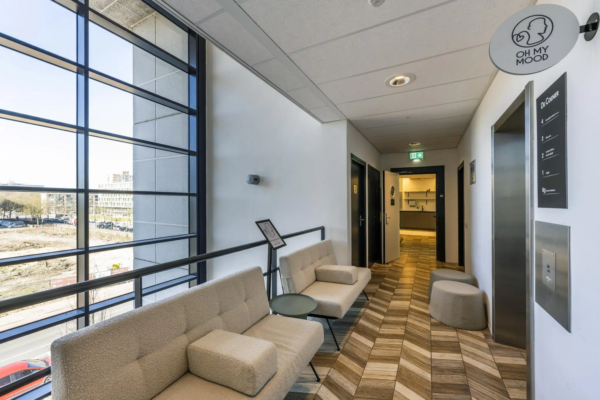 Wachtruimte van het kantoorgebouw aan de Overschiestraat met moderne zitbanken, grote ramen en het logo van 'Oh My Mood'.