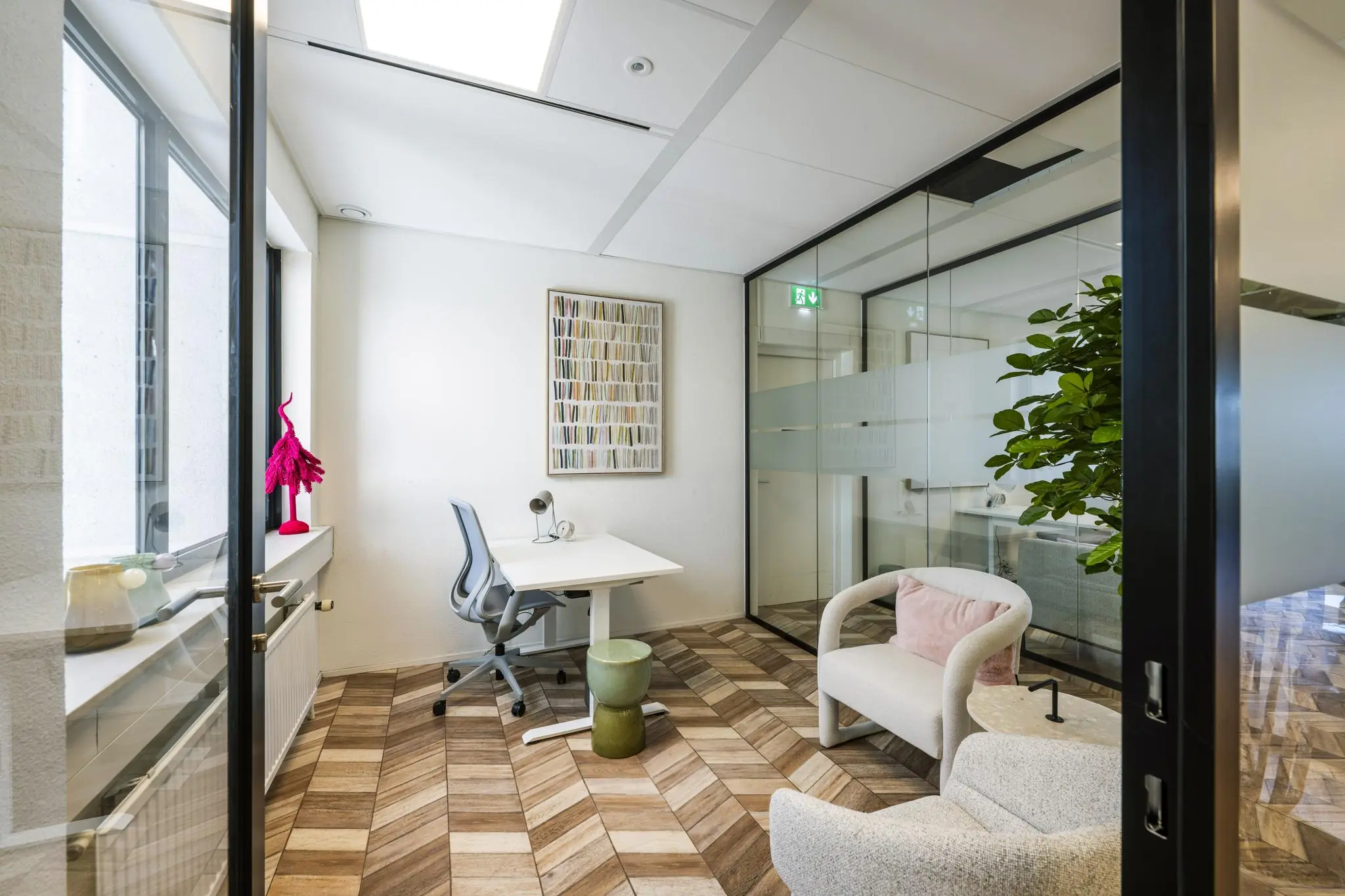 Modern ingerichte kantoorruimte aan de Overschiestraat met glazen wanden, houten visgraatvloer en stijlvolle meubels.